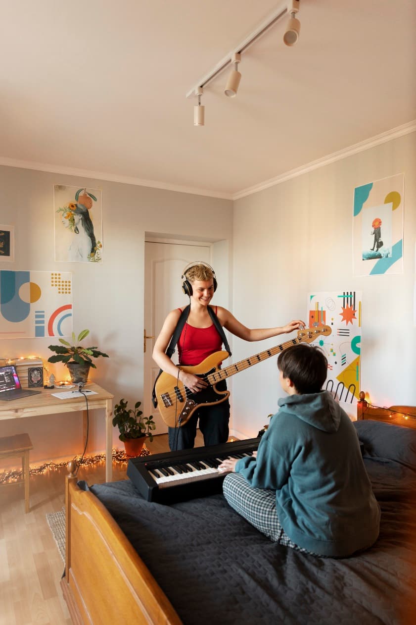 Zwei junge Menschen machen gemeinsam Musik in einem gemütlichen Wohnraum - Symbol für Lebensorte und Gemeinschaft